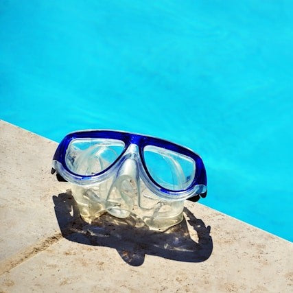 This is a picture of white swimming goggles placed in a swimming pool.